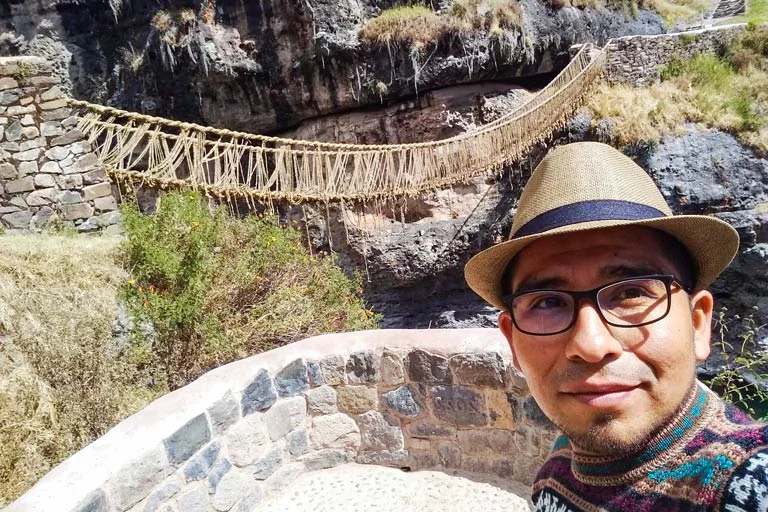 Visitante sacándose selfi con el Puente Q’eswachaka de fondo